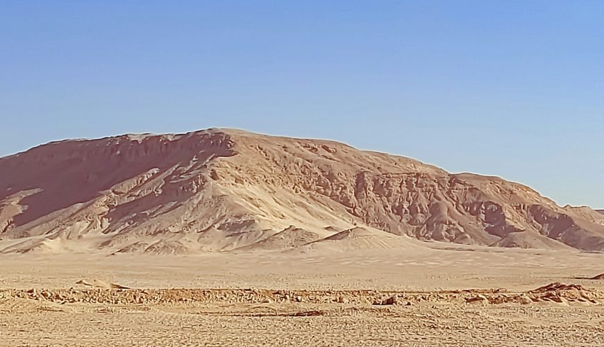 a desert landscape with a mountain in the background